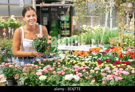 Jeune femme choisissant des roses de brousse dans le magasin de fleurs Banque D'Images