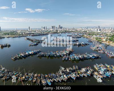 Vue aérienne de bateaux de pêche colorés ancrés dans la baie de Da Nang, Da Nang, Vietnam, avec une ligne d'horizon moderne sous un ciel bleu clair. Banque D'Images