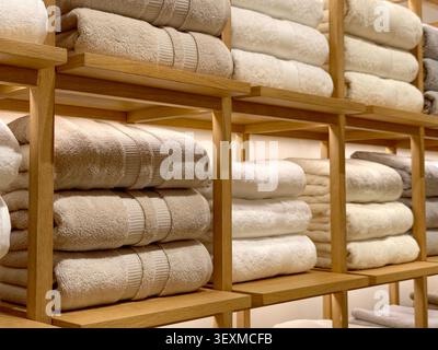 Serviettes beige et blanche soigneusement pliées sur des étagères en bois Banque D'Images