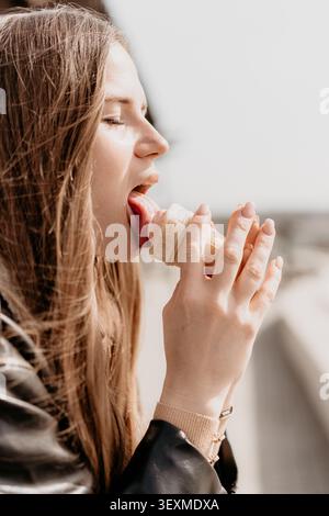 Femme profil de léchage de crème glacée d'une jeune femme appréciant une friandise sucrée à l'extérieur par une journée ensoleillée Banque D'Images