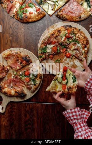 Une jeune femme prend une tranche de pizza fraîchement cuite. Isolé. Éclairage de studio professionnel. Banque D'Images