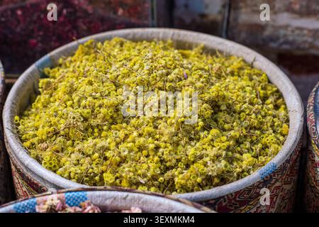 Gros plan au-dessus d'un grand panier rempli de petites fleurs jaunes séchées et de leurs tiges minces. La composition met en valeur la texture naturelle A. Banque D'Images