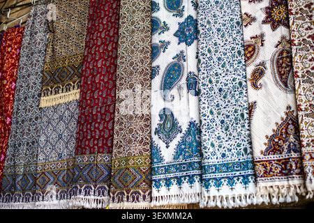 Gros plan de magnifiques textiles en coton imprimés à la main affichés verticalement. L'image met en évidence des motifs floraux et géométriques Paisley denses dans l'alose Banque D'Images