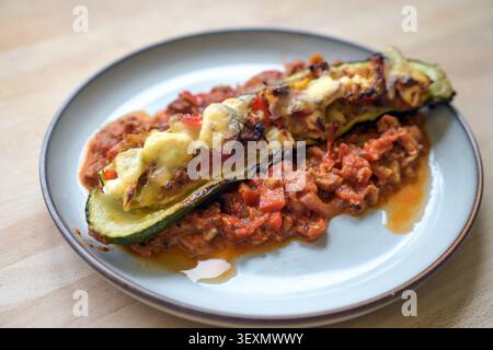Bateau de courgettes du four rempli de poivrons, thon, oignons et feta sur la salsa de tomate servie dans une assiette, repas sain fait maison à faible teneur en glucides, selecte Banque D'Images