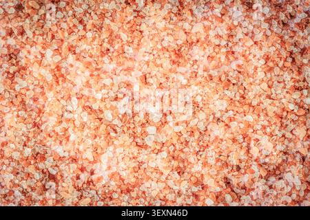 Texture en gros plan de cristaux de sel rose de l'Himalaya, fond de sel minéral naturel dans des tons rose doux, blanc et orange pour le spa, le bien-être et la beauté de Banque D'Images