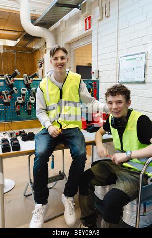 Portrait d'un jeune homme souriant assis à côté d'un ami masculin dans un atelier professionnel Banque D'Images