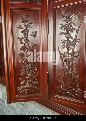 Panneaux en bois sculptés avec motifs floraux et bambou. Des sculptures en bois asiatiques traditionnelles complexes représentant des fleurs, des papillons et des oiseaux sur une étale de bambou Banque D'Images
