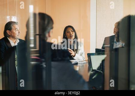 Professionnel des affaires féminin discutant des idées avec l'équipe dans la salle de réunion au bureau Banque D'Images