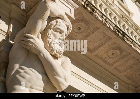 Vue en contre-plongée d'une statue historique d'atlante Omenoni en pierre à l'entrée du Grand Palais à Lugano. Banque D'Images