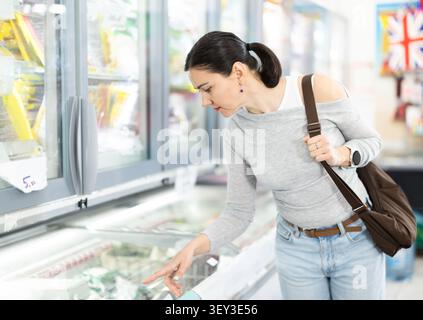 Jeune femme choisissant la nourriture congelée dans l'épicerie Banque D'Images