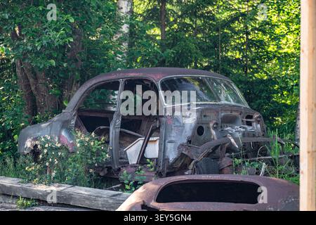 Carrosserie de voiture vintage abandonnée recouverte de rouille en attente de restauration dans un atelier automobile extérieur Banque D'Images