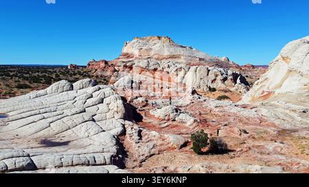Badlands panoramiques en grès sous Blue Sky. Vue panoramique des formations de grès blanc et rouge avec des crêtes en couches, terrain désertique érodé, clairsemé Banque D'Images