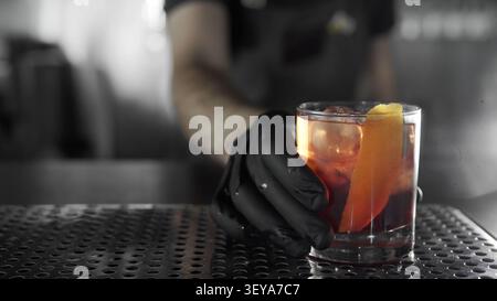 Le barman sert un cocktail Negroni classique avec une garniture d'écorce d'orange et une boisson rafraîchissante Banque D'Images