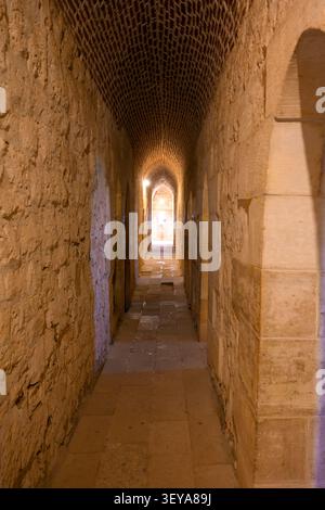 Une vue intérieure donnant sur un étroit couloir de pierre ensoleillé avec des plafonds voûtés historiques à l'intérieur de la citadelle de Qaitbay, un défenseur emblématique du XVe siècle Banque D'Images