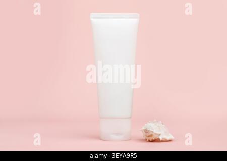 Vue avant du tube de crème de bouteille blanche sans marque et coquillage sur fond rose. Cosmétiques avec calcium et sel de mer. Maquette, modèle, closeu Banque D'Images
