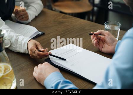 Professionnel féminin montrant la ligne de signature sur le contrat au client Banque D'Images