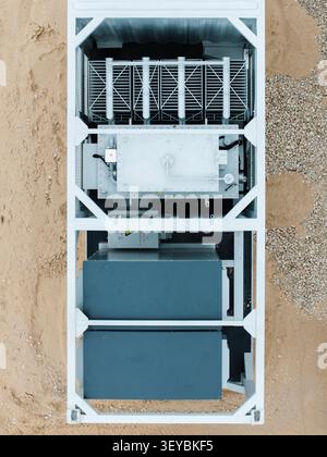 Vue aérienne d'un transformateur électrique industriel logé dans un cadre métallique sur un sol sablonneux en Lettonie. Banque D'Images