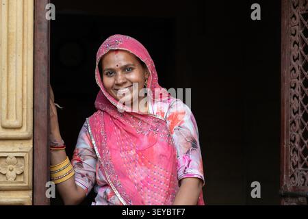 Femme souriante portant des vêtements traditionnels debout dans une porte à Jaisalmer, en Inde Banque D'Images