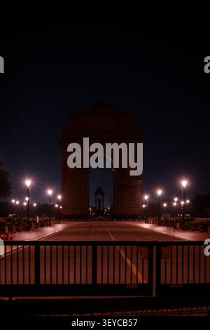 India Gate illuminé la nuit avec une avenue cérémonielle vide et des lampadaires lumineux à New Delhi, en Inde. Banque D'Images
