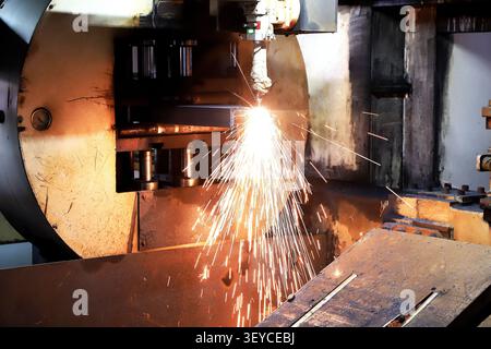 Un gros plan spectaculaire d'une machine de découpe plasma CNC en fonctionnement, libérant une douche brillante d'étincelles blanches-chaudes alors qu'elle tranche à travers l'acier lourd pl Banque D'Images