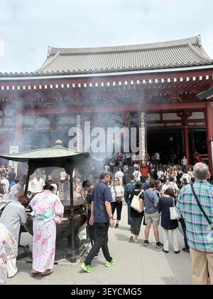 Les visiteurs se rassemblent autour du brûleur d'encens (koro) au temple bouddhiste Senso-ji, Asakusa, Tokyo, Japon. Femmes en kimono visibles parmi la foule. Banque D'Images
