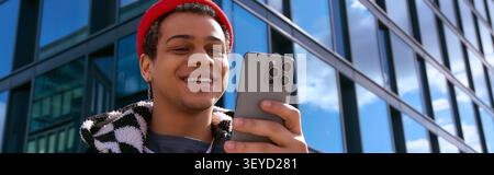 Un jeune homme élégant envoie des SMS heureux dans un cadre urbain dynamique. Banque D'Images