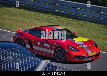 Voiture de sport Porsche 718 Cayman rouge avec livrée de jour de piste RSR Nürburg conduite sur la Nordschleife Nürburgring lors d'une séance de conduite touristique. Banque D'Images