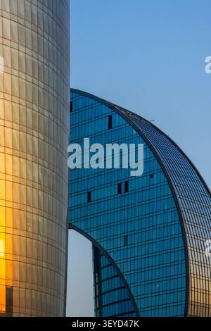 Gros plan sur les façades en verre incurvées de la Tour 2 de Port Baku avec le reflet doré du coucher du soleil et le Crescent Hotel en forme de croissant. Bakou, Azerbaïdjan. Banque D'Images