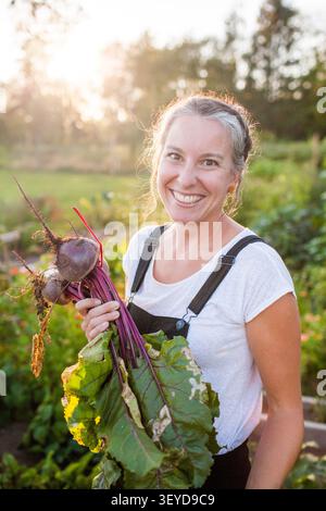 Femme heureuse tenant la récolte de betteraves fraîches au coucher du soleil Banque D'Images