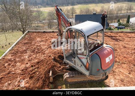 Le godet de la pelle hydraulique, rempli d'argile et de pierres, creuse le sol lorsque la machine fonctionne sur site. Cet équipement puissant prépare le terrain Banque D'Images