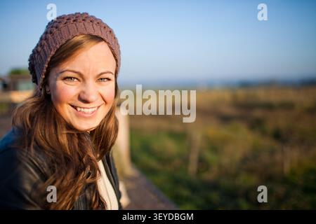 Heureuse jeune femme dans un bonnet sourit dehors Banque D'Images