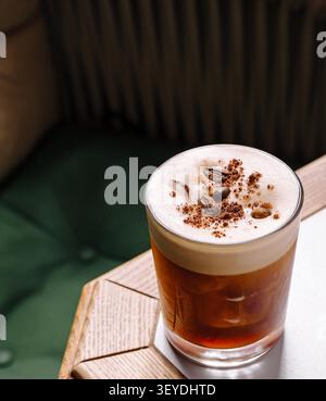 Cocktail espresso martini présentant une boisson riche au café avec mousse, poudre de cacao et grains de café Banque D'Images