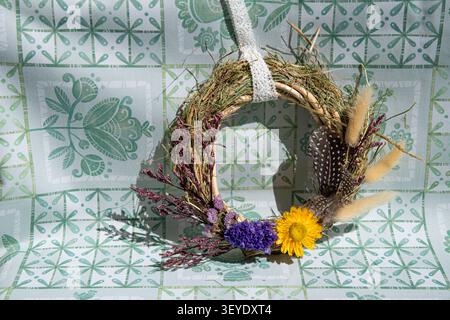 Couronne artisanale ornée de fleurs séchées et d'herbes dans un style rustique Banque D'Images