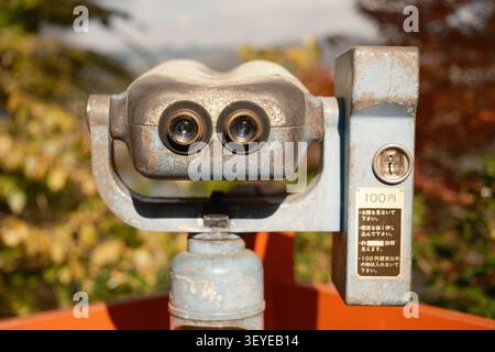 Vue rapprochée d'une rue montrant une machine télescope à vision binoculaire métallique à pièces, devant des feuilles d'automne, Kyoto, Japon Banque D'Images