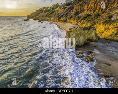 Vue aérienne d'El Matador State Beach avec ses formations rocheuses emblématiques, ses falaises dorées et ses vagues écrasantes au coucher du soleil à Malibu, Californie, États-Unis Banque D'Images