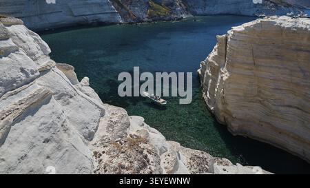 Un bateau glisse dans une eau bleu turquoise entourée de falaises impressionnantes, de roches volcaniques blanches, de roches blanches bizarres dans la mer, de Little Sarakiniko, Ki Banque D'Images