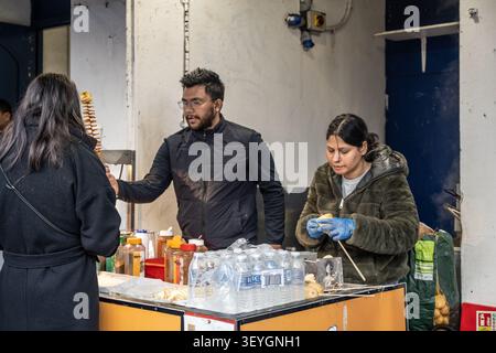 Vendeurs de nourriture de rue préparant des chips de pommes de terre en spirale sur un stand de marché en plein air sur Portobello Road à Notting Hill, Londres, Royaume-Uni. Banque D'Images