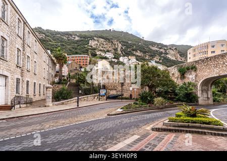 Vue urbaine à Gibraltar près des portes de Southport. La photo montre une rue pavée, des bâtiments historiques en pierre, des parterres de fleurs, un vieux canon défensif, et t Banque D'Images