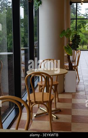 Intérieur de café moderne avec de grandes fenêtres et des meubles en bois minimalistes Banque D'Images