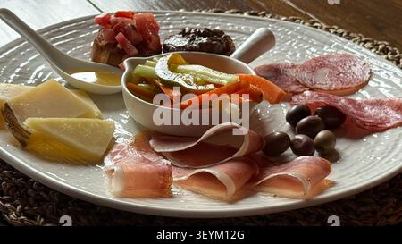 Assiette de charcuterie avec viandes tranchées, fromage, olives et légumes. Comprend du prosciutto, du salami, des quartiers de fromage et une variété de légumes frais Banque D'Images