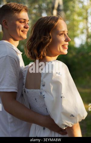 Un jeune couple heureux partage un moment tendre à l'extérieur, baigné dans la lueur chaude de la lumière du coucher du soleil Banque D'Images