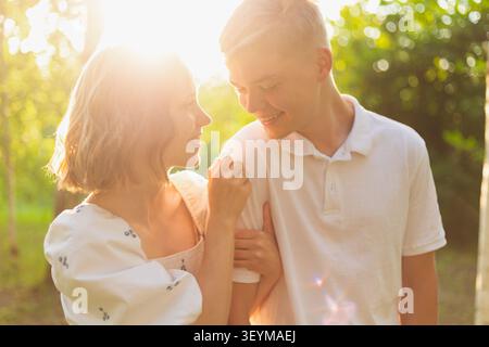Un couple partage un moment tendre dans une forêt ensoleillée, soulignant leur amour et leur connexion Banque D'Images