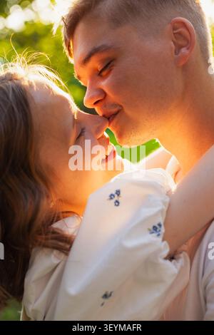 Un couple romantique embrasse étroitement, leurs visages illuminés par la lueur chaude du soleil couchant, capturant un moment d'affection profonde et de connexion o Banque D'Images