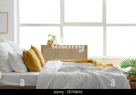 Chambre lumineuse avec literie blanche et oreillers moutarde Banque D'Images