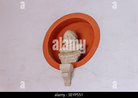 Séville, Espagne. Détail du buste médiéval en pierre du XIVe siècle du roi Pedro I de Castille à l'intérieur d'une niche circulaire orange sur un mur blanc à la Banque D'Images