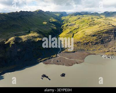 Vue aérienne du glacier Solheimajokull avec une rivière qui coule à travers une vallée verdoyante dans un lagon glaciaire à Myrdalshreppur, Islande. Banque D'Images