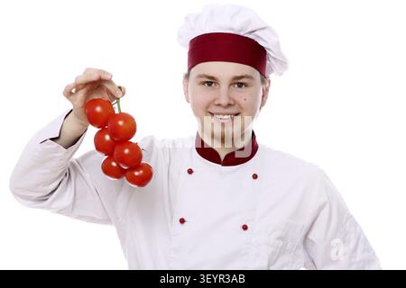 Jeune chef avec des tomates sur fond blanc Banque D'Images