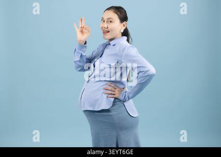 Femme enceinte faisant un geste de signe de main OK dans un studio photo professionnel ... Banque D'Images