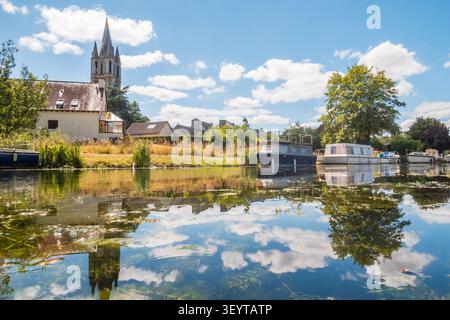 La ville d'Evran, les bateaux sur le canal de l'Ille-et-Rance, et le clocher de l'église Saint-Pierre en Bretagne. Banque D'Images