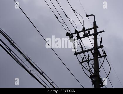 Des lignes électriques aériennes et un poteau électrique silhouettent contre un ciel couvert dans Mullae Artist Village, Corée du Sud. Banque D'Images